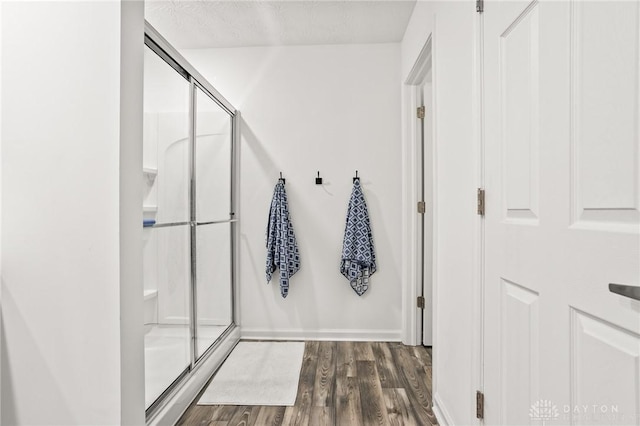 full bath featuring wood finished floors, a stall shower, and baseboards