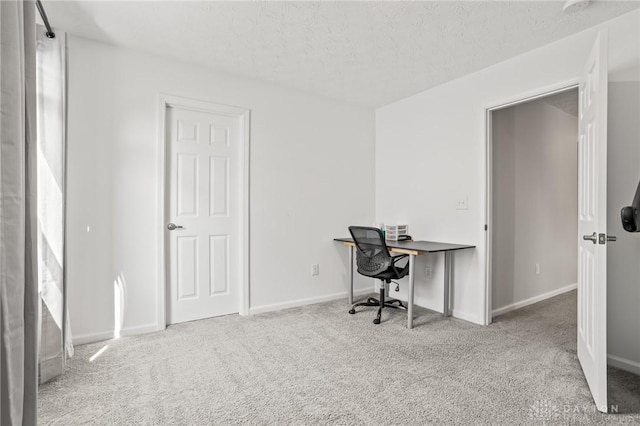 carpeted office space featuring a textured ceiling and baseboards