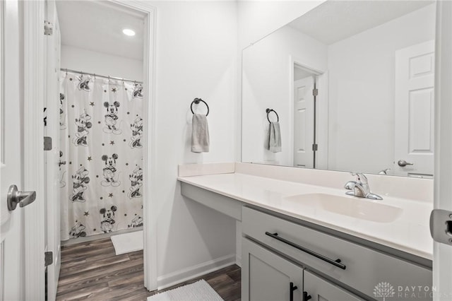full bath featuring wood finished floors, vanity, baseboards, and a shower with shower curtain