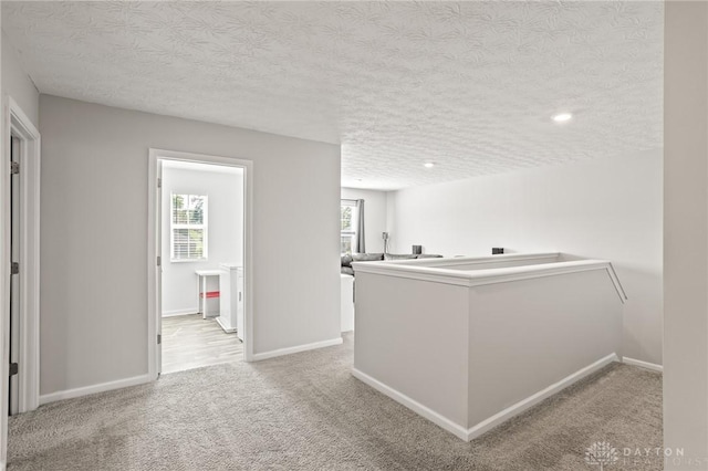 hallway featuring a textured ceiling, plenty of natural light, carpet floors, baseboards, and recessed lighting
