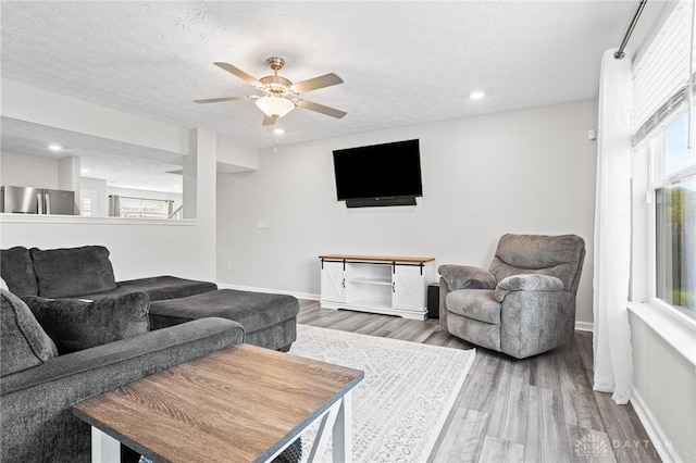 living room with wood finished floors, a ceiling fan, baseboards, and recessed lighting