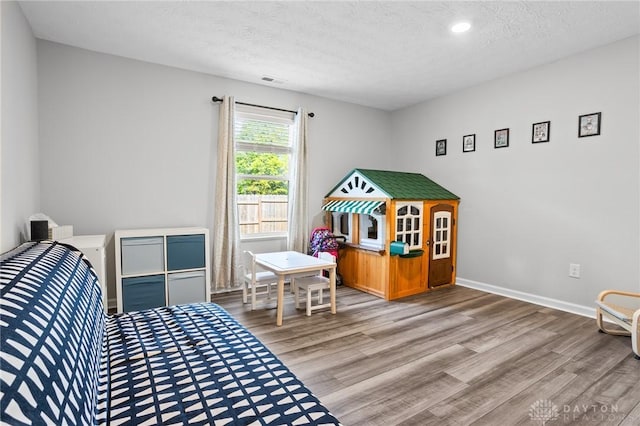 bedroom with wood finished floors, a textured ceiling, baseboards, and recessed lighting