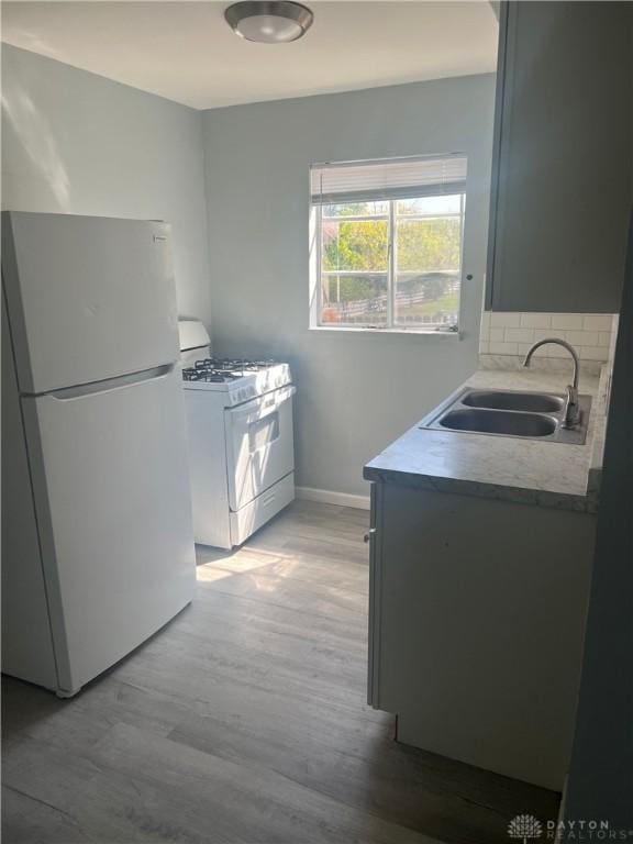 1155 Linda Vista Ave, Dayton, OH 45405 - kitchen with white appliances, a sink, light wood-type flooring, baseboards, and light countertops