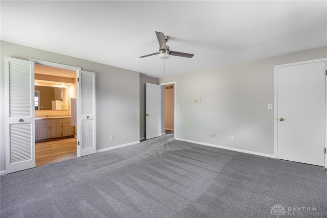 unfurnished bedroom with carpet flooring, baseboards, ensuite bath, and ceiling fan