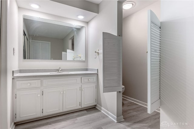 bathroom with wood finished floors, toilet, baseboards, and vanity