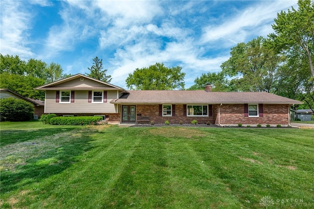 tri-level home with french doors, brick siding, a chimney, and a front lawn