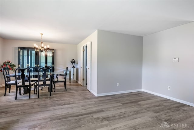 dining space with a chandelier, wood finished floors, and baseboards