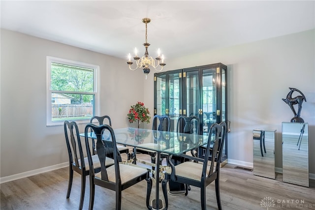 dining area with a chandelier, wood finished floors, and baseboards