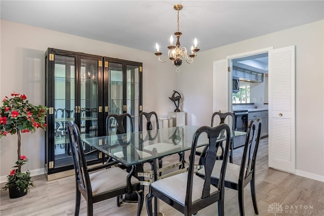 dining space featuring a chandelier, light wood-style floors, french doors, and baseboards