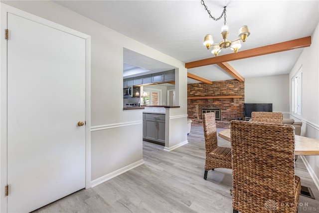 dining space with a chandelier, beam ceiling, light wood-style flooring, a fireplace, and baseboards