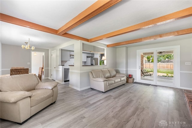 living area featuring a chandelier, light wood-style flooring, beamed ceiling, and baseboards