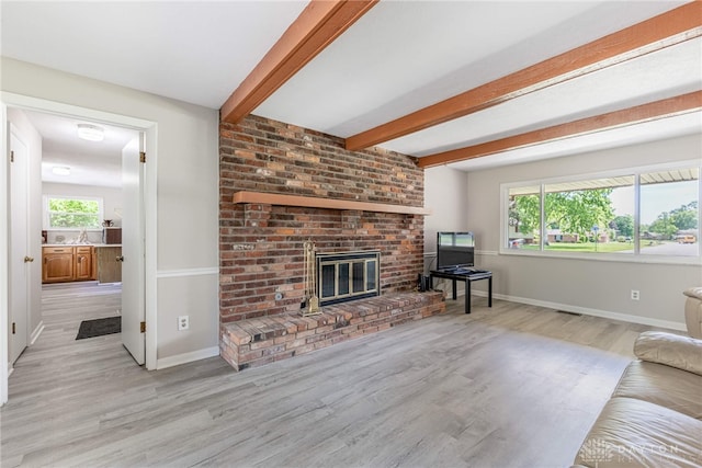 living room with wood finished floors, a fireplace, baseboards, and beamed ceiling