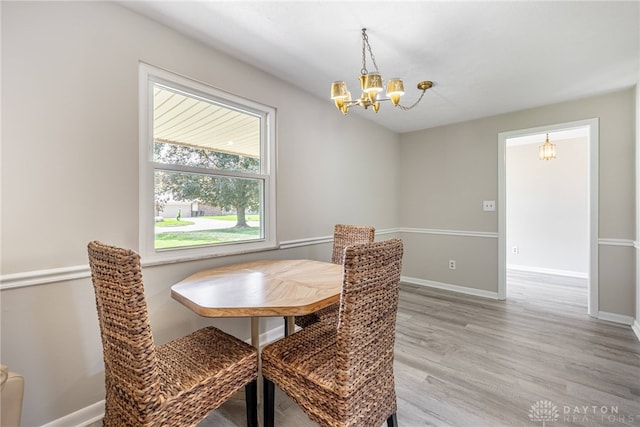 dining room featuring a chandelier, light wood finished floors, and baseboards