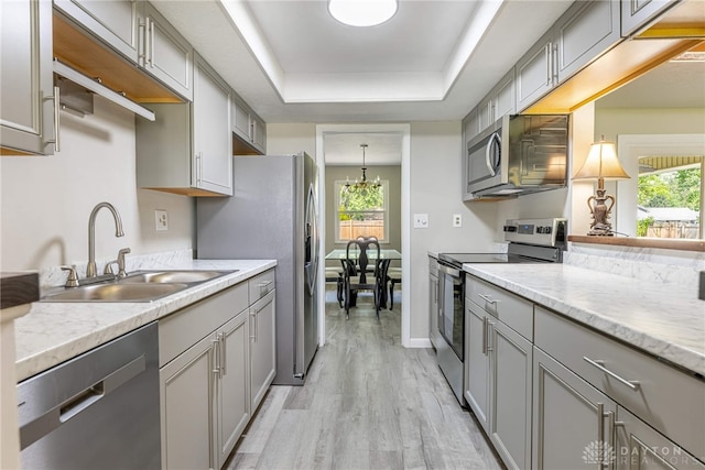 kitchen with stainless steel appliances, a sink, gray cabinetry, light wood finished floors, and healthy amount of natural light
