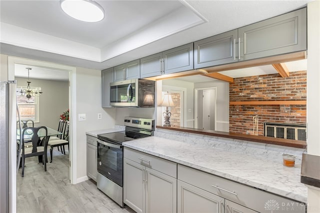 kitchen featuring stainless steel appliances, gray cabinets, light wood finished floors, baseboards, and a chandelier