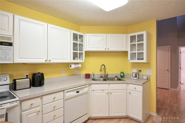 4826 Beechwood Ln, Middletown, OH 45042 - kitchen featuring white appliances, a sink, light wood finished floors, white cabinetry, and a textured ceiling