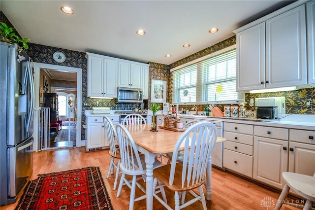 401 Hadley Ave, Dayton, OH 45419 - kitchen featuring appliances with stainless steel finishes, white cabinets, light wood finished floors, backsplash, and wallpapered walls