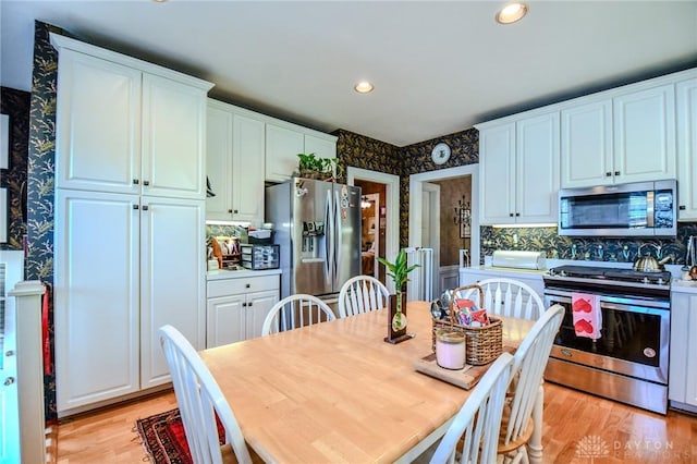401 Hadley Ave, Dayton, OH 45419 - kitchen with stainless steel appliances, white cabinets, light wood finished floors, wallpapered walls, and backsplash