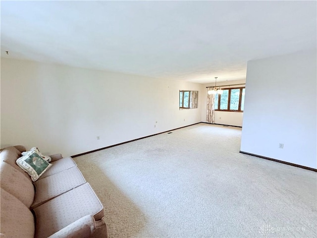 5778 Cedarwood Dr, Lewisburg, OH 45338 - unfurnished living room with light colored carpet, baseboards, and a chandelier
