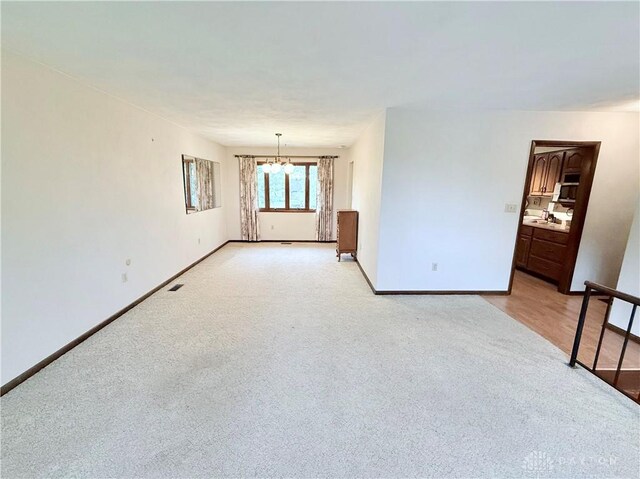 5778 Cedarwood Dr, Lewisburg, OH 45338 - spare room with light colored carpet, baseboards, and a chandelier