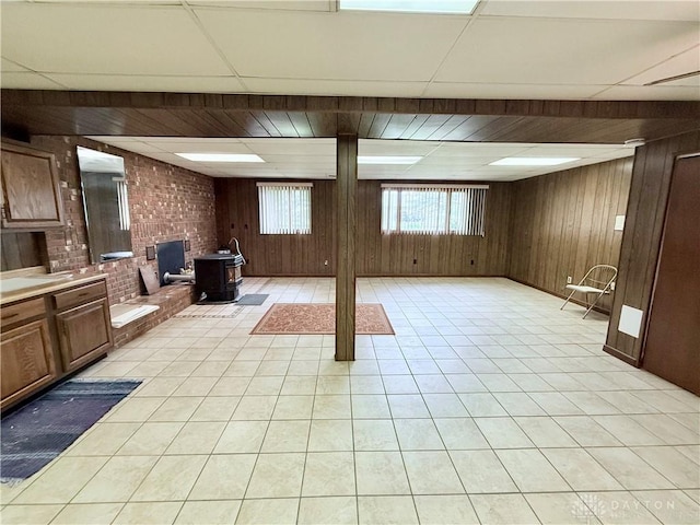 5778 Cedarwood Dr, Lewisburg, OH 45338 - basement with a wood stove, wooden walls, brick wall, light tile patterned floors, and a drop ceiling