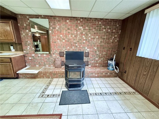 5778 Cedarwood Dr, Lewisburg, OH 45338 - bathroom with a wood stove, a drop ceiling, wooden walls, tile patterned floors, and brick wall