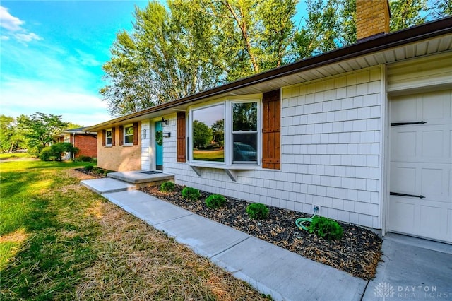 4189 W Franklin St, Bellbrook, OH 45305 - view of exterior entry featuring a chimney and a yard