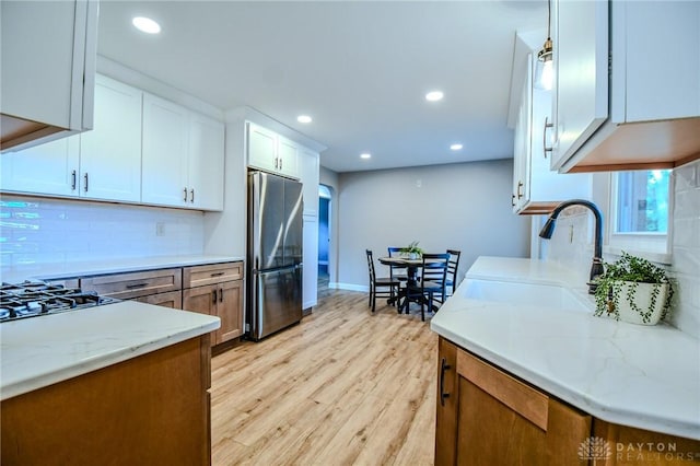 4189 W Franklin St, Bellbrook, OH 45305 - kitchen with freestanding refrigerator, cooktop, tasteful backsplash, light wood-style floors, and light stone counters
