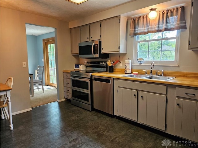 2547 Ryan Ct, Beavercreek, OH 45434 - kitchen featuring stainless steel appliances, a sink, light countertops, a textured ceiling, and baseboards