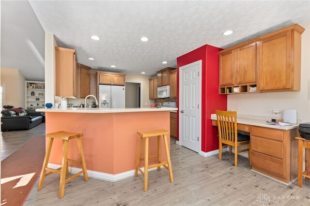 9300 Somerset Ct, Clearcreek Twp, OH 45458 - kitchen featuring fridge with ice dispenser, white microwave, a peninsula, light wood-style flooring, and recessed lighting