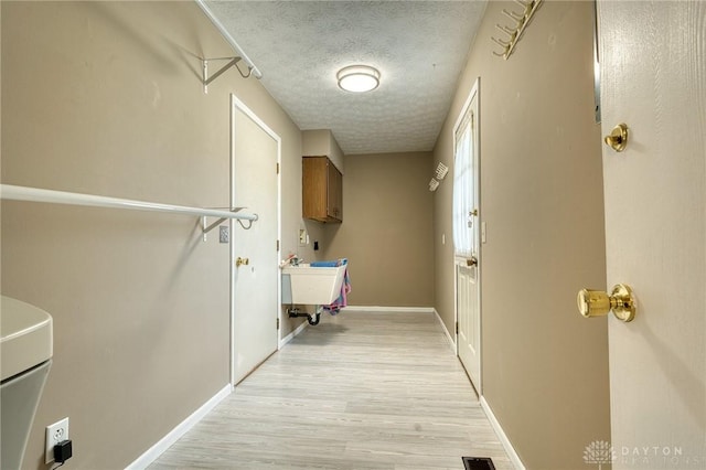 3339 Turner Dr, Springfield, OH 45504 - laundry area featuring light wood-type flooring, cabinet space, a textured ceiling, and baseboards
