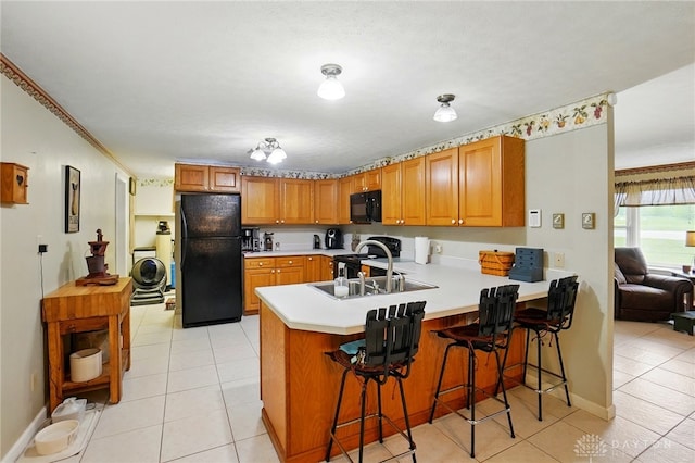 8590 Euphemia Castine Rd, Lewisburg, OH 45338 - kitchen featuring black appliances, a peninsula, light countertops, light tile patterned floors, and brown cabinetry