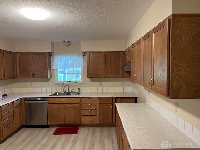 125 Honeysuckle Way, Eaton, OH 45320 - kitchen with dishwasher, a sink, a textured ceiling, light wood finished floors, and brown cabinets