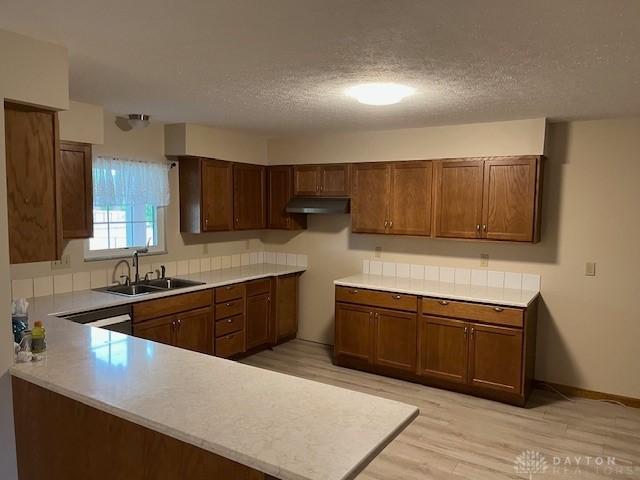 125 Honeysuckle Way, Eaton, OH 45320 - kitchen with a sink, under cabinet range hood, light wood-type flooring, a textured ceiling, and a peninsula
