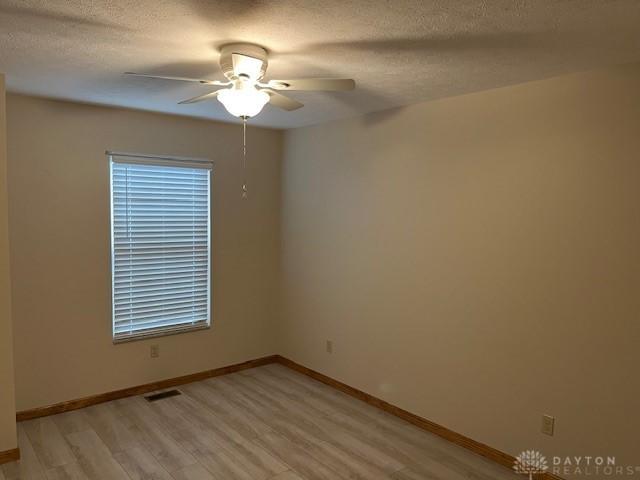 125 Honeysuckle Way, Eaton, OH 45320 - empty room with light wood-style floors, ceiling fan, baseboards, and a textured ceiling