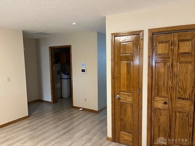 125 Honeysuckle Way, Eaton, OH 45320 - hallway with light wood-type flooring, baseboards, water heater, and a textured ceiling
