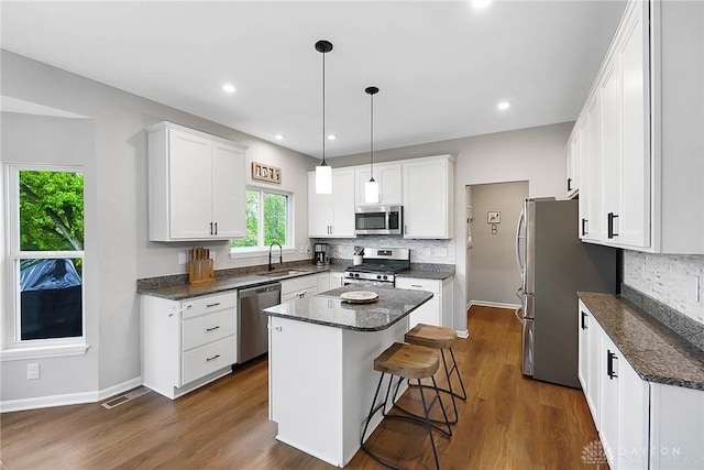 1691 Arden Bnd, Fairborn, OH 45324 - kitchen with stainless steel appliances, a kitchen island, tasteful backsplash, white cabinetry, and dark wood-style flooring
