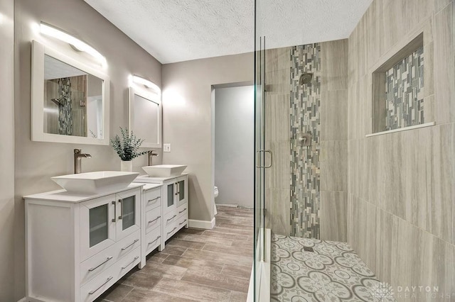406 Forge Dr, Lebanon, OH 45036 - full bath featuring a shower stall, double vanity, toilet, a textured ceiling, and baseboards