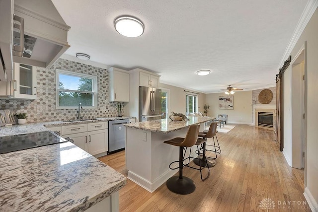 406 Forge Dr, Lebanon, OH 45036 - kitchen featuring appliances with stainless steel finishes, a kitchen breakfast bar, a sink, light wood-type flooring, and crown molding