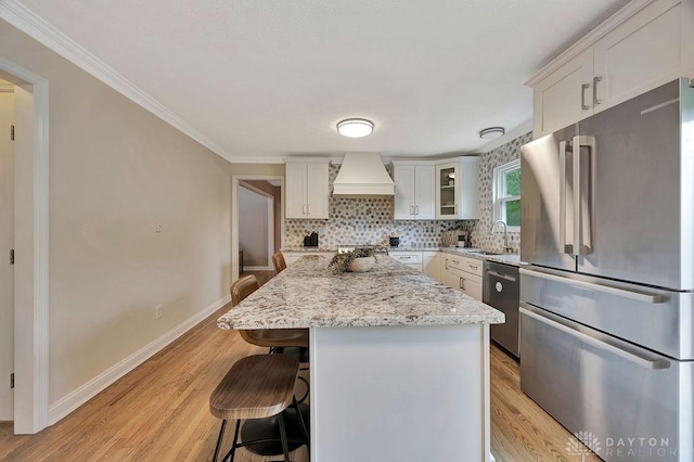406 Forge Dr, Lebanon, OH 45036 - kitchen with appliances with stainless steel finishes, premium range hood, a sink, a kitchen bar, and light wood-style flooring
