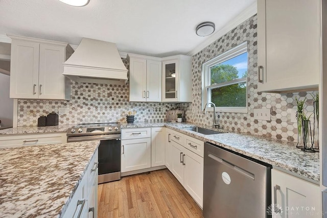 406 Forge Dr, Lebanon, OH 45036 - kitchen featuring appliances with stainless steel finishes, custom range hood, a sink, light wood-type flooring, and light stone counters