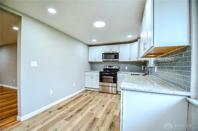 3653 Cloverdale Rd, Medway, OH 45341 - kitchen with stainless steel appliances, a sink, light wood-type flooring, light stone counters, and backsplash
