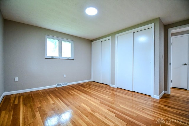 3653 Cloverdale Rd, Medway, OH 45341 - unfurnished bedroom with multiple closets, baseboards, and wood finished floors
