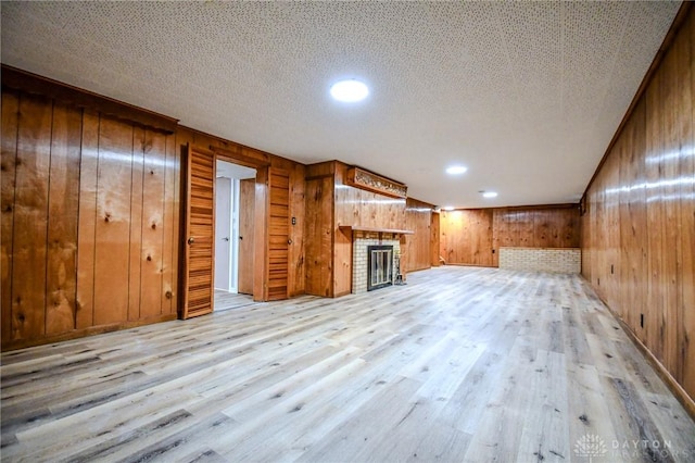 3653 Cloverdale Rd, Medway, OH 45341 - unfurnished living room featuring wood walls, light wood-style flooring, a fireplace, and recessed lighting