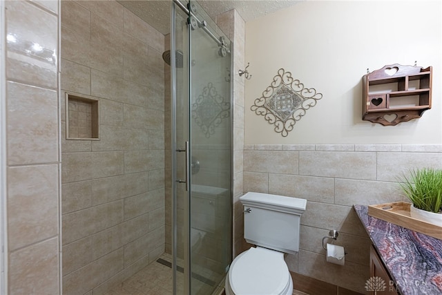 2444 Tennyson Dr, Bellbrook, OH 45305 - bathroom featuring tile walls, toilet, a stall shower, a textured ceiling, and vanity