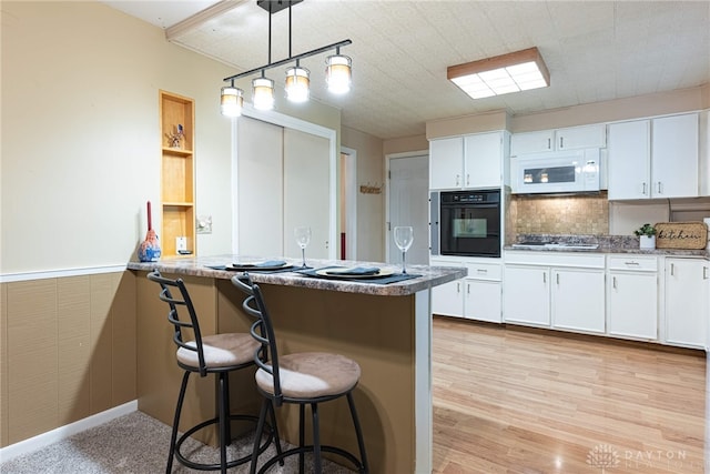 2444 Tennyson Dr, Bellbrook, OH 45305 - kitchen with black oven, white microwave, gas cooktop, white cabinets, and a kitchen breakfast bar