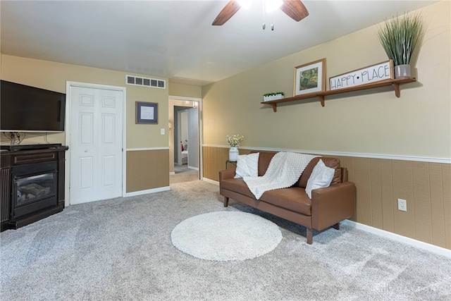 2444 Tennyson Dr, Bellbrook, OH 45305 - carpeted living area with ceiling fan, a wainscoted wall, and a glass covered fireplace