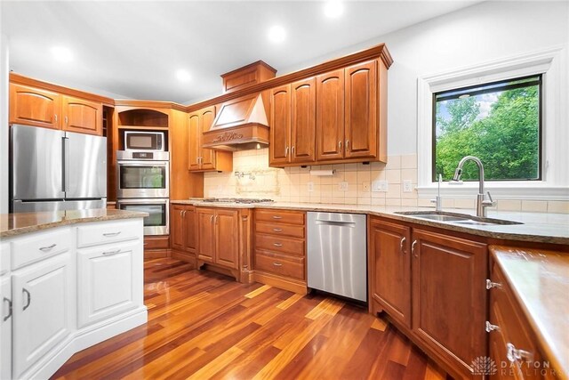 7721 Country Brook Ct, Springboro, OH 45066 - kitchen featuring appliances with stainless steel finishes, a sink, dark wood-type flooring, custom exhaust hood, and tasteful backsplash