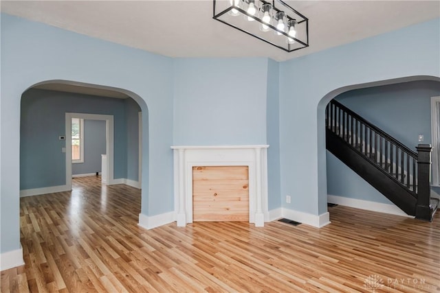 1015 Maiden Ln, Springfield, OH 45504 - unfurnished living room with arched walkways, wood finished floors, baseboards, and stairs