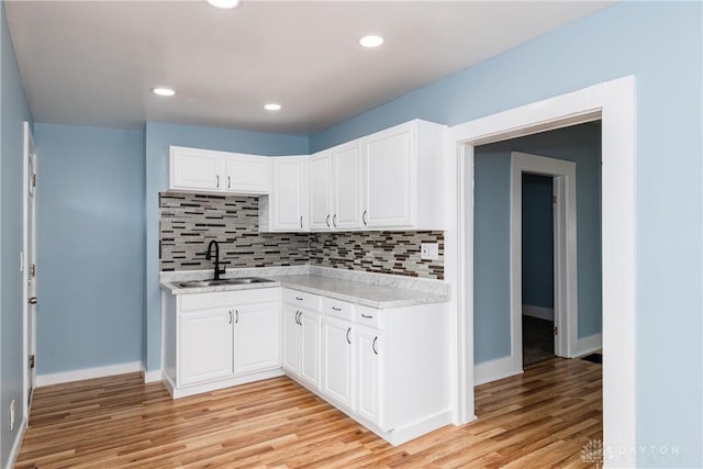 1015 Maiden Ln, Springfield, OH 45504 - kitchen with light countertops, a sink, light wood-style flooring, decorative backsplash, and recessed lighting